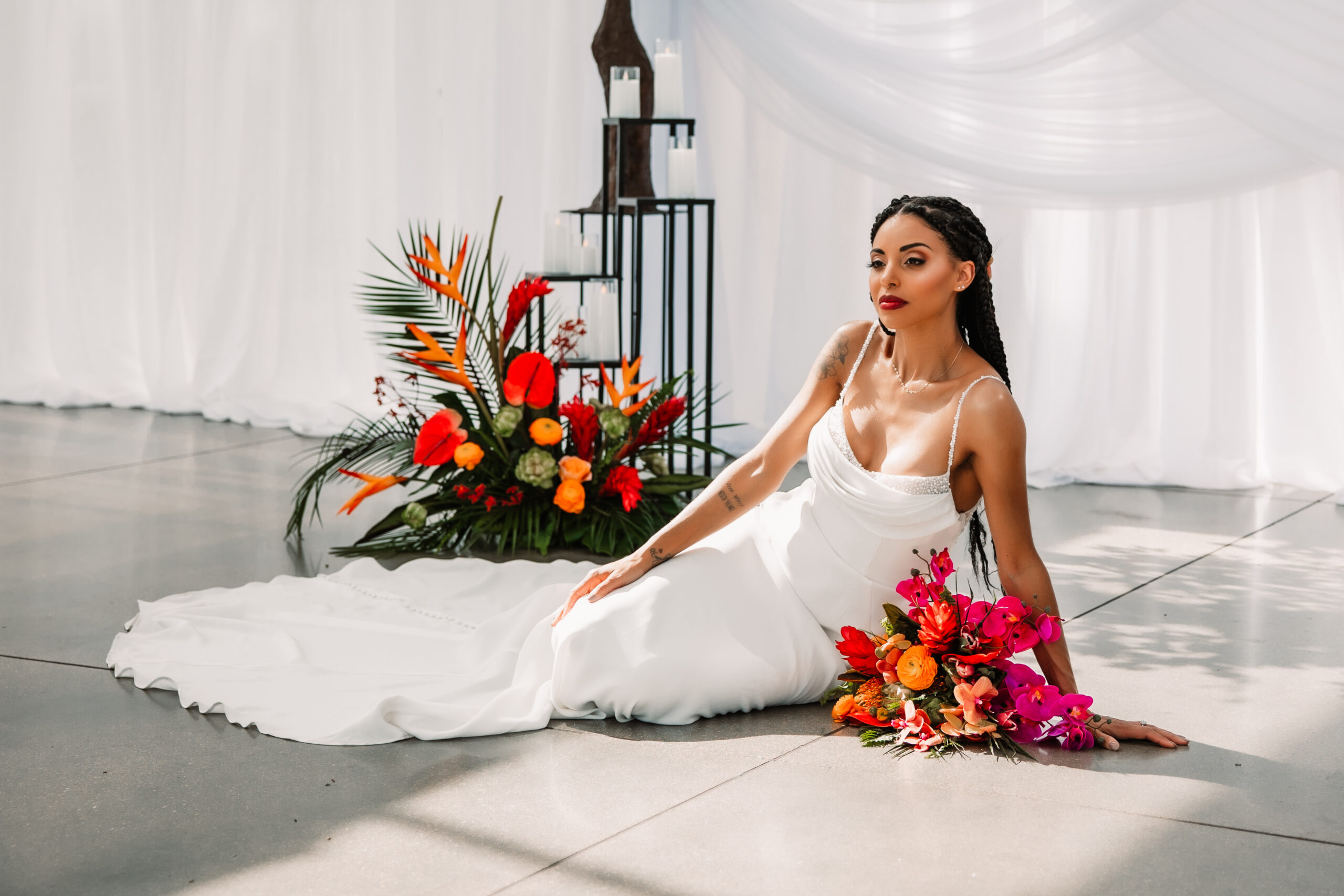 bride sits on floor with florals and white drapery