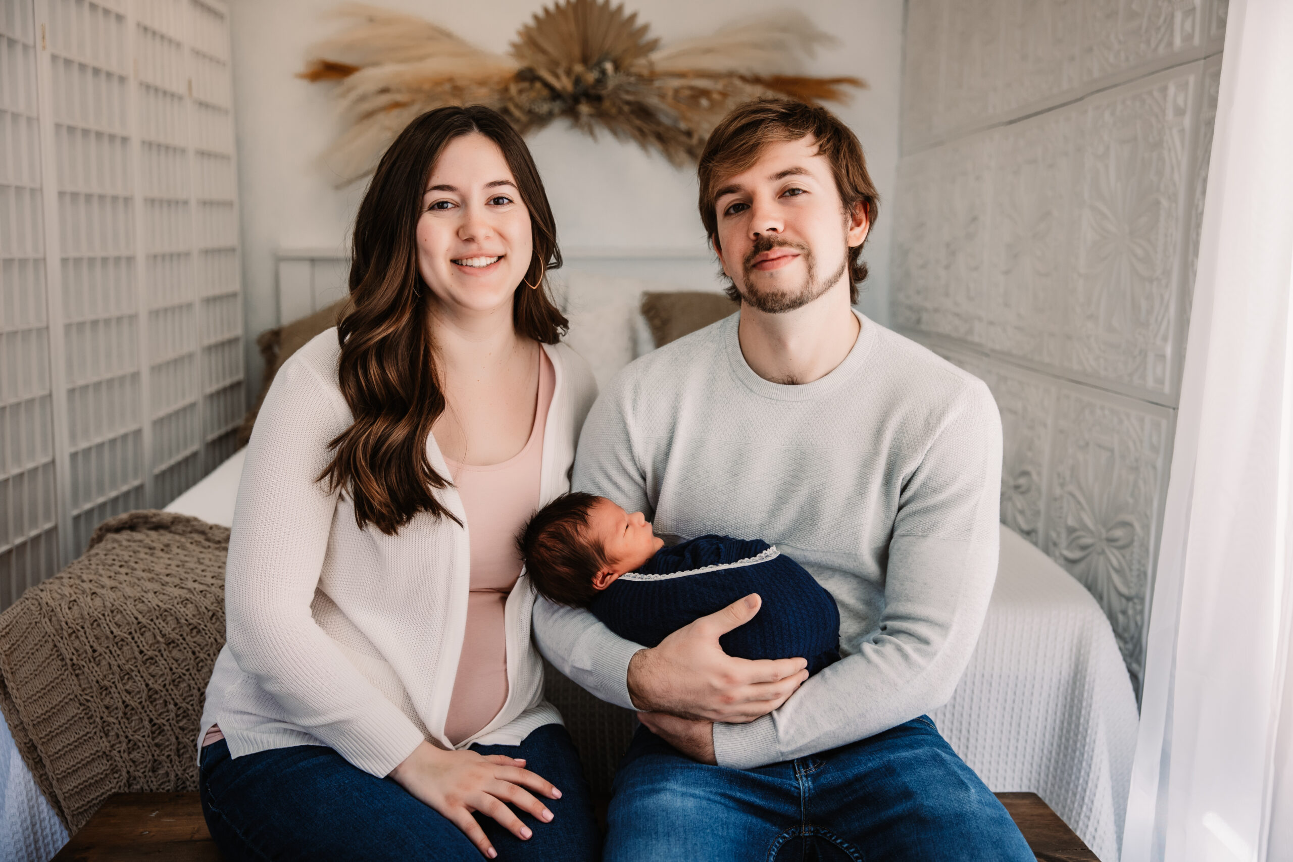 mom and dad hold baby boy in boho studio set