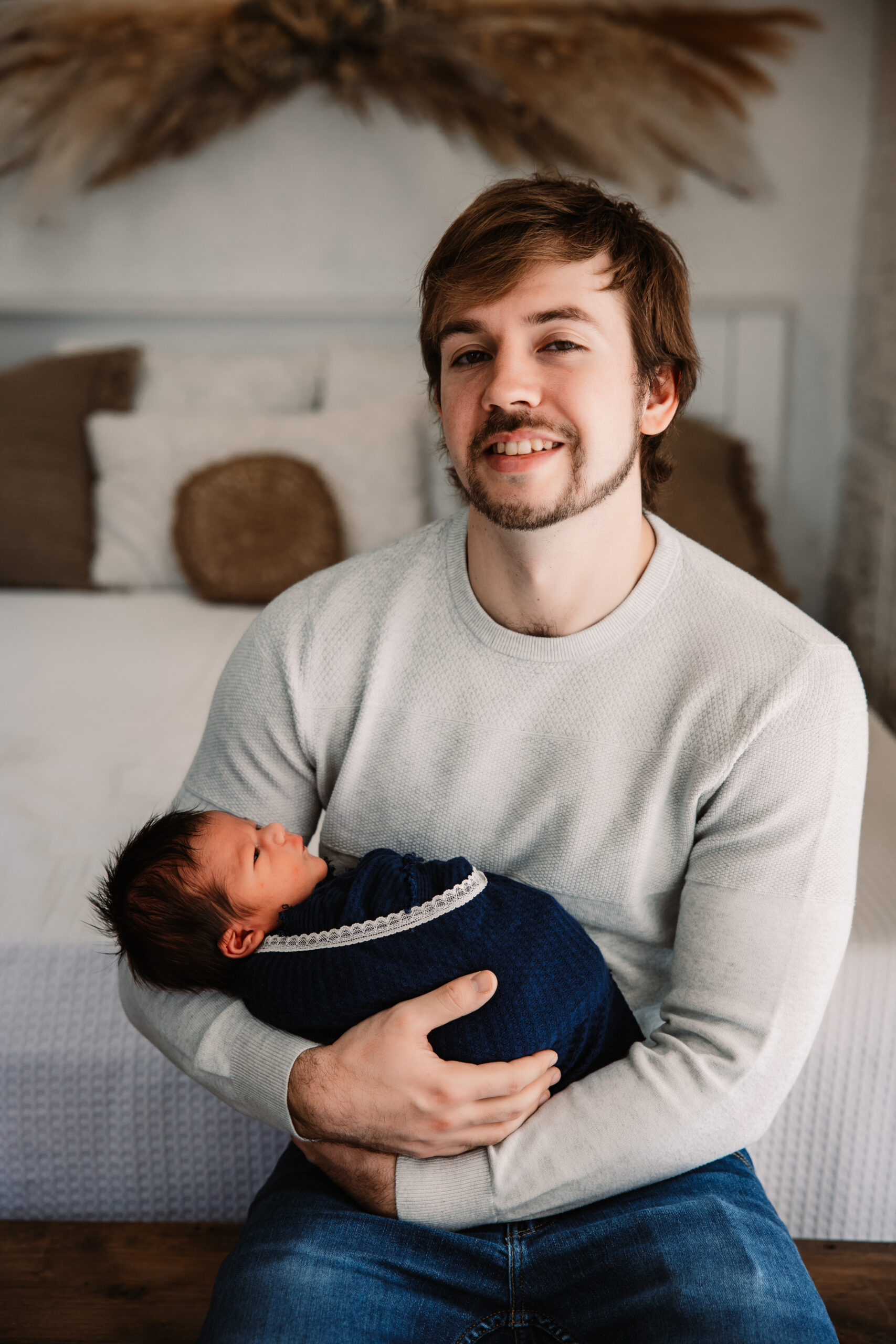 young dad holds wrapped baby in blue