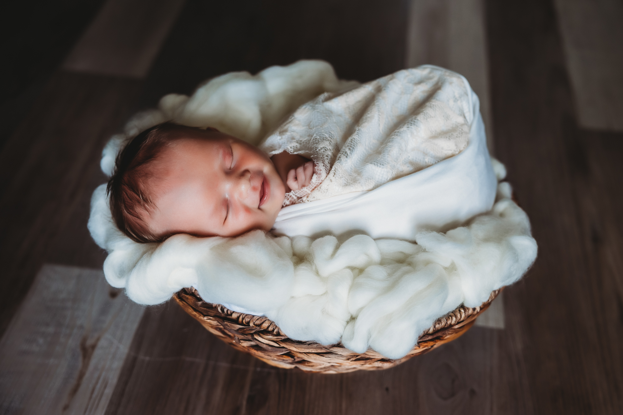 newborn baby girl in basket with tan blankets